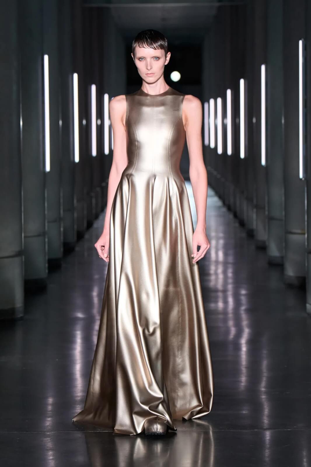 Model wearing gold metallic dress on runway
