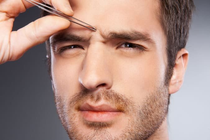 Man tweezing his eyebrow hair