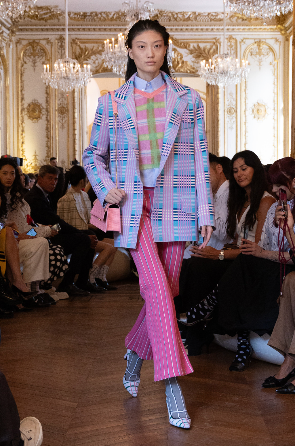 a person wearing a pink and purple suit and standing in front of a crowd of people